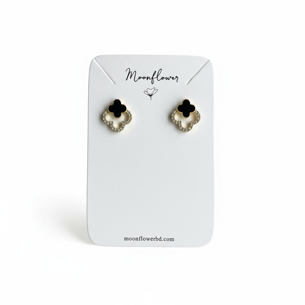Pair of black and gold flower-shaped earrings on a Moonflower branded card.