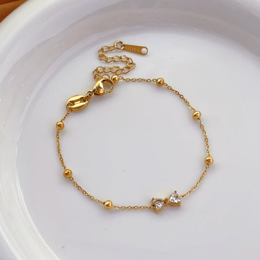 Gold bracelet with small crystals on a white plate