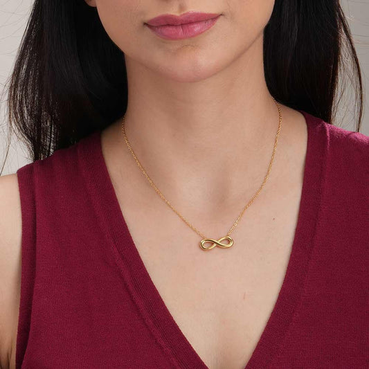Woman wearing a gold necklace with an infinity symbol pendant.