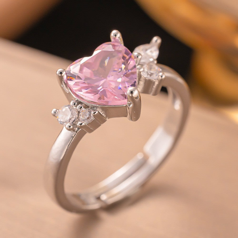 Silver ring with a pink heart-shaped gemstone on a beige background