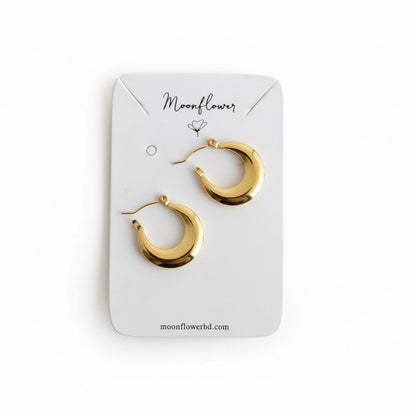 Gold hoop earrings on a 'Moonflower' branded card against a wooden background