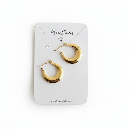 Gold hoop earrings on a 'Moonflower' branded card against a wooden background