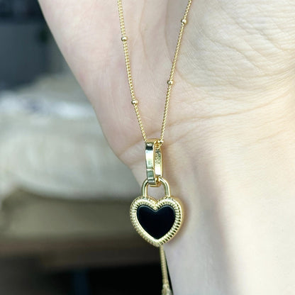 Gold necklace with a black heart pendant on a blurred background