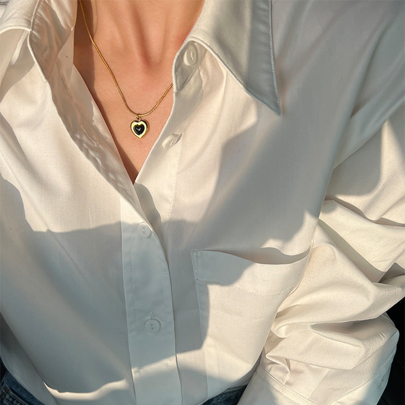 White shirt with a gold necklace featuring a heart pendant