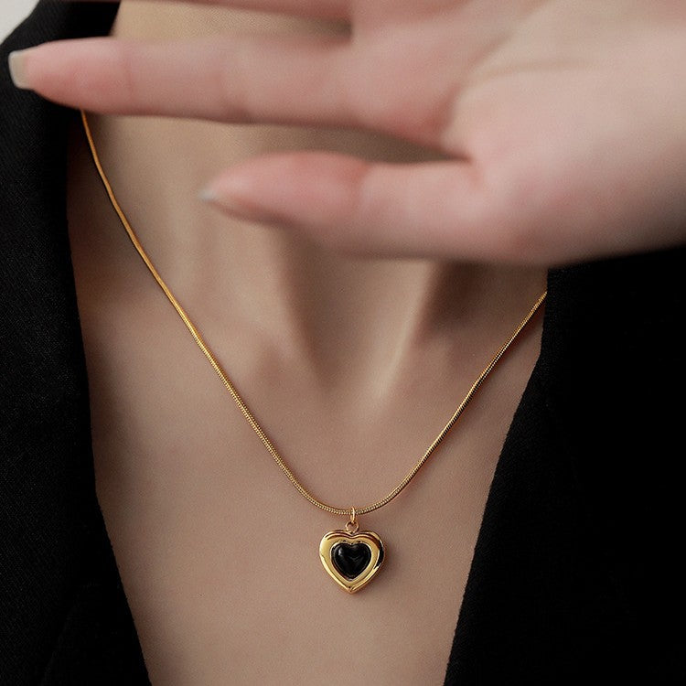 Gold necklace with a heart-shaped pendant worn by a person