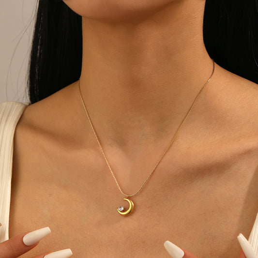 Gold necklace with a moon and star pendant on a person's neck against a neutral background