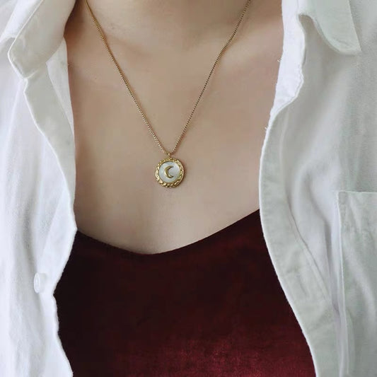 Necklace with a pendant worn by a person wearing a white shirt and maroon top.