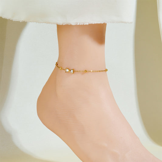 Gold anklet on a person's ankle against a neutral background