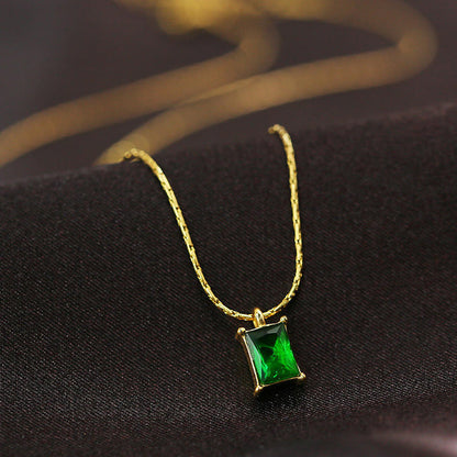Gold necklace with a green gemstone pendant on a dark fabric background