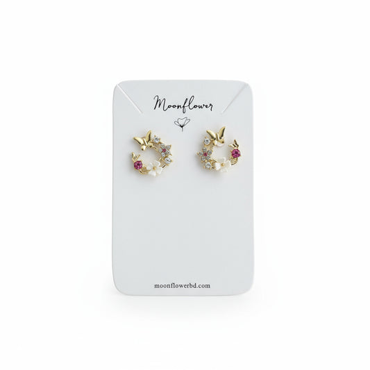 Pair of gold earrings with gemstones on a Moonflower branded card.