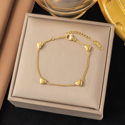 Gold bracelet with heart-shaped charms on a beige jewelry box