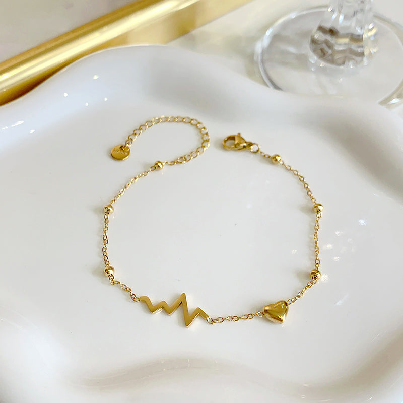 Gold bracelet with wave design on a white dish