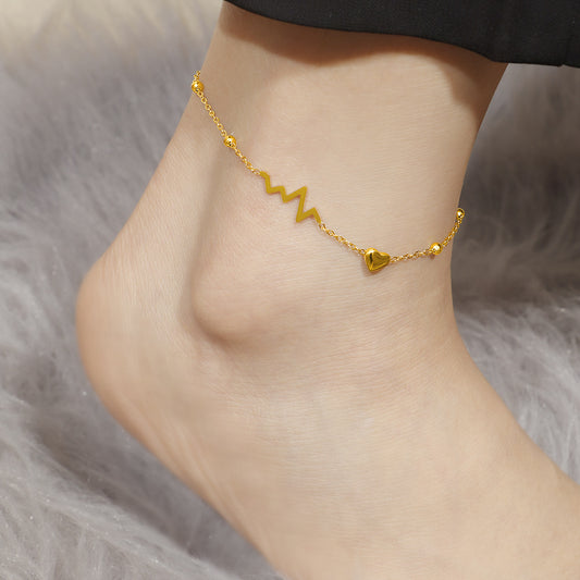 Gold anklet on a person's ankle against a soft gray background