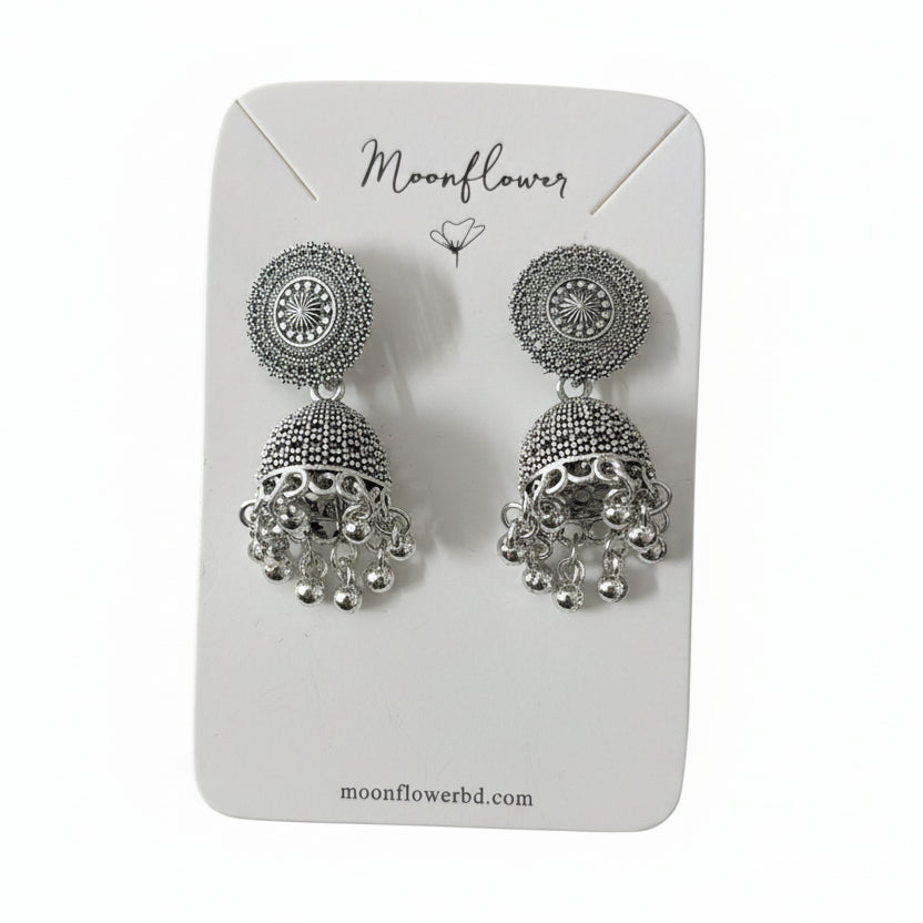 Silver earrings on a Moonflower branded card held by a black gloved hand.