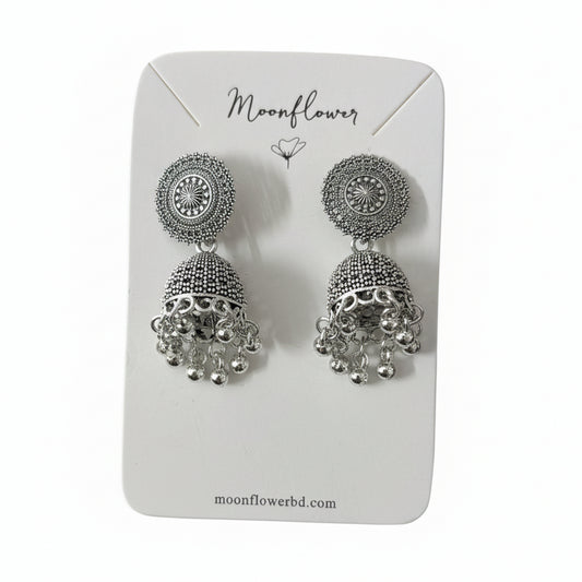 Silver earrings on a Moonflower branded card held by a black gloved hand.