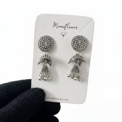 Silver earrings on a 'Moonflower' branded card held by a dark sleeve.