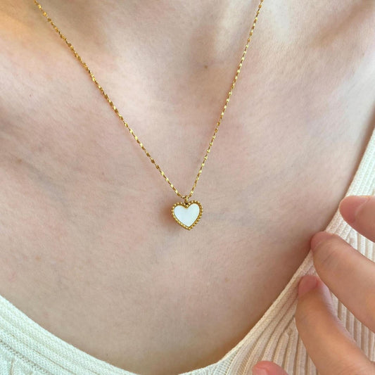 Gold necklace with a heart-shaped pendant worn by a person