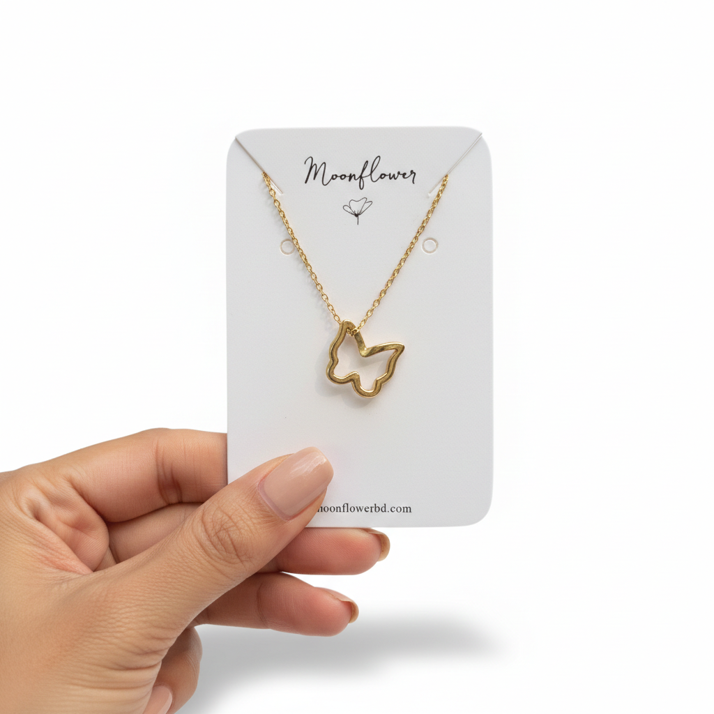 Gold butterfly necklace on a 'Moonflower' branded card held by a hand against a white background
