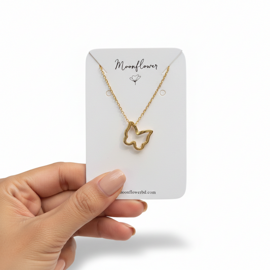 Gold butterfly necklace on a 'Moonflower' branded card held by a hand against a white background