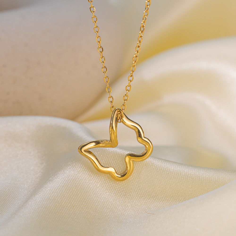 Gold necklace with a butterfly-shaped pendant on a soft beige fabric background