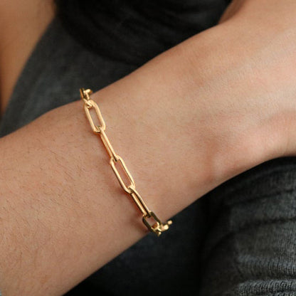 Gold chain bracelet on a wrist with a blurred background