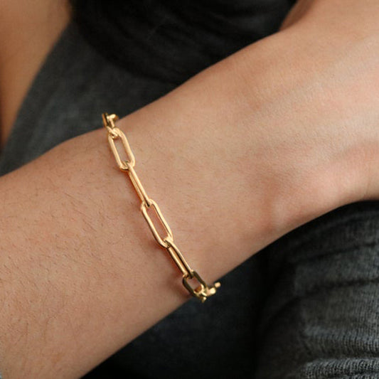 Gold chain bracelet on a wrist with a blurred background