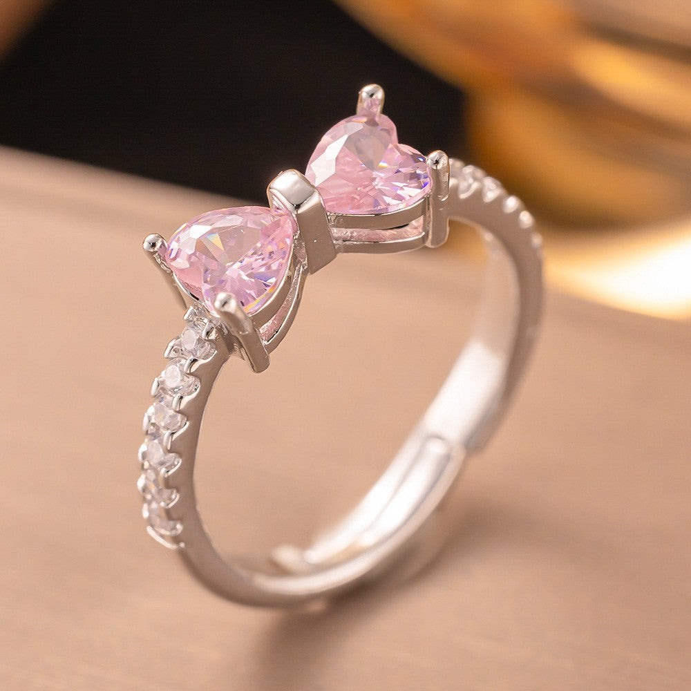 Silver ring with pink heart-shaped gemstones on a soft background