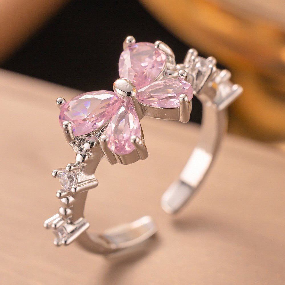 Silver ring with pink gemstones on a beige background