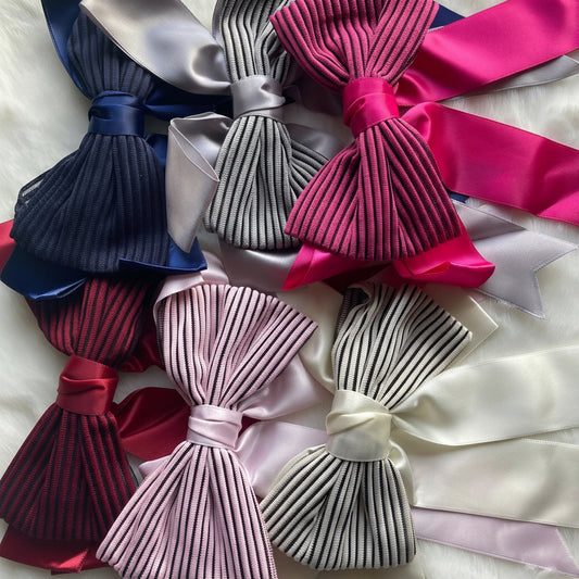 Collection of colorful satin hair bows on a textured surface