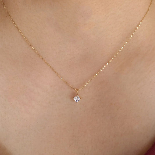 Gold necklace with a small diamond pendant on a person's neck