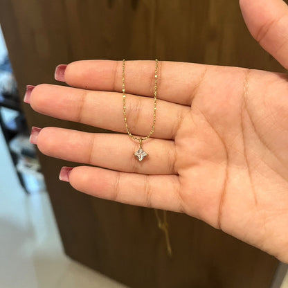 Gold necklace with a star-shaped pendant held in a hand against a blurred background