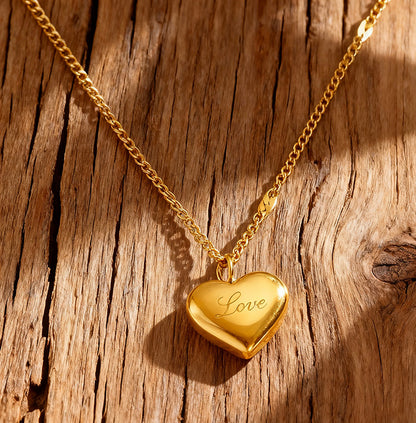Gold heart-shaped locket with 'Love' engraving on a wooden surface