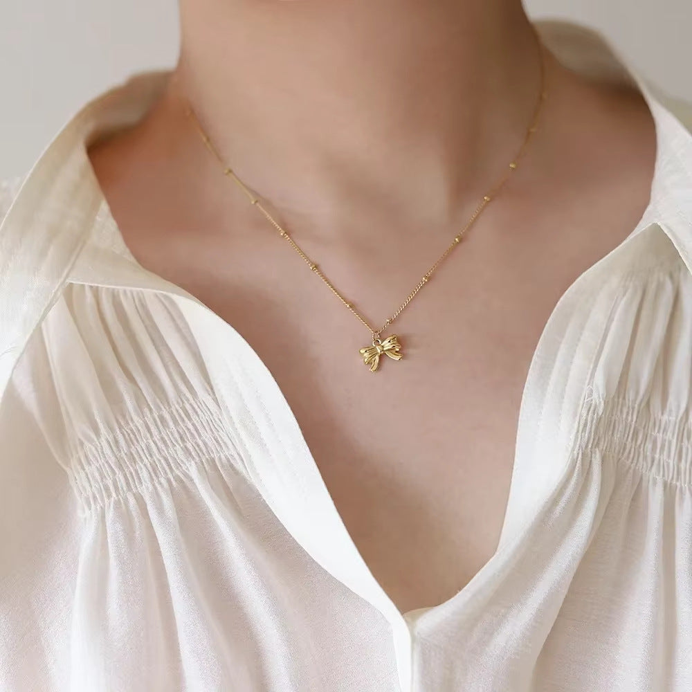 Gold necklace with a delicate pendant on a white blouse
