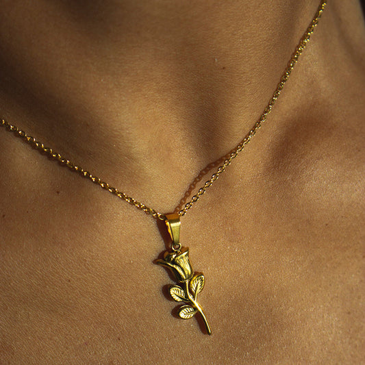 Gold necklace with a rose pendant on a person's neck