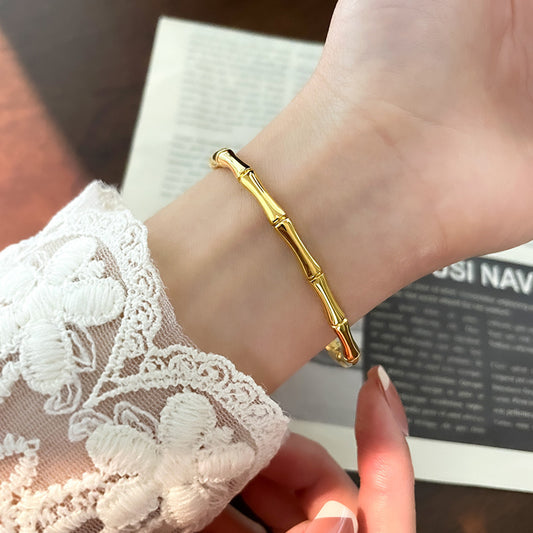 Gold bracelet on a wrist with lace-trimmed sleeve